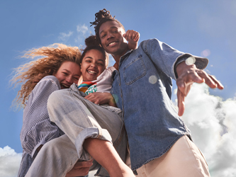 A family of three embracing in front of blue sky